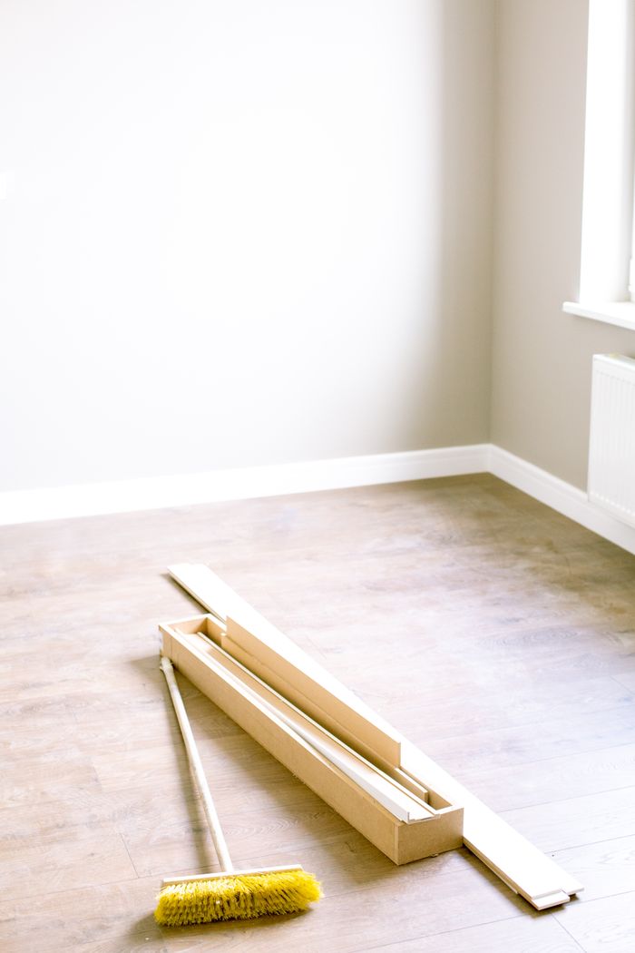An empty room with wooden planks and a broom, prepared for renovation.